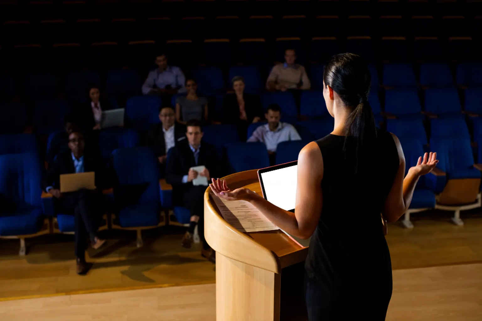 Une rédactrice prépare le discours d’un dirigeant sur son ordinateur, avec des notes et un carnet de travail.