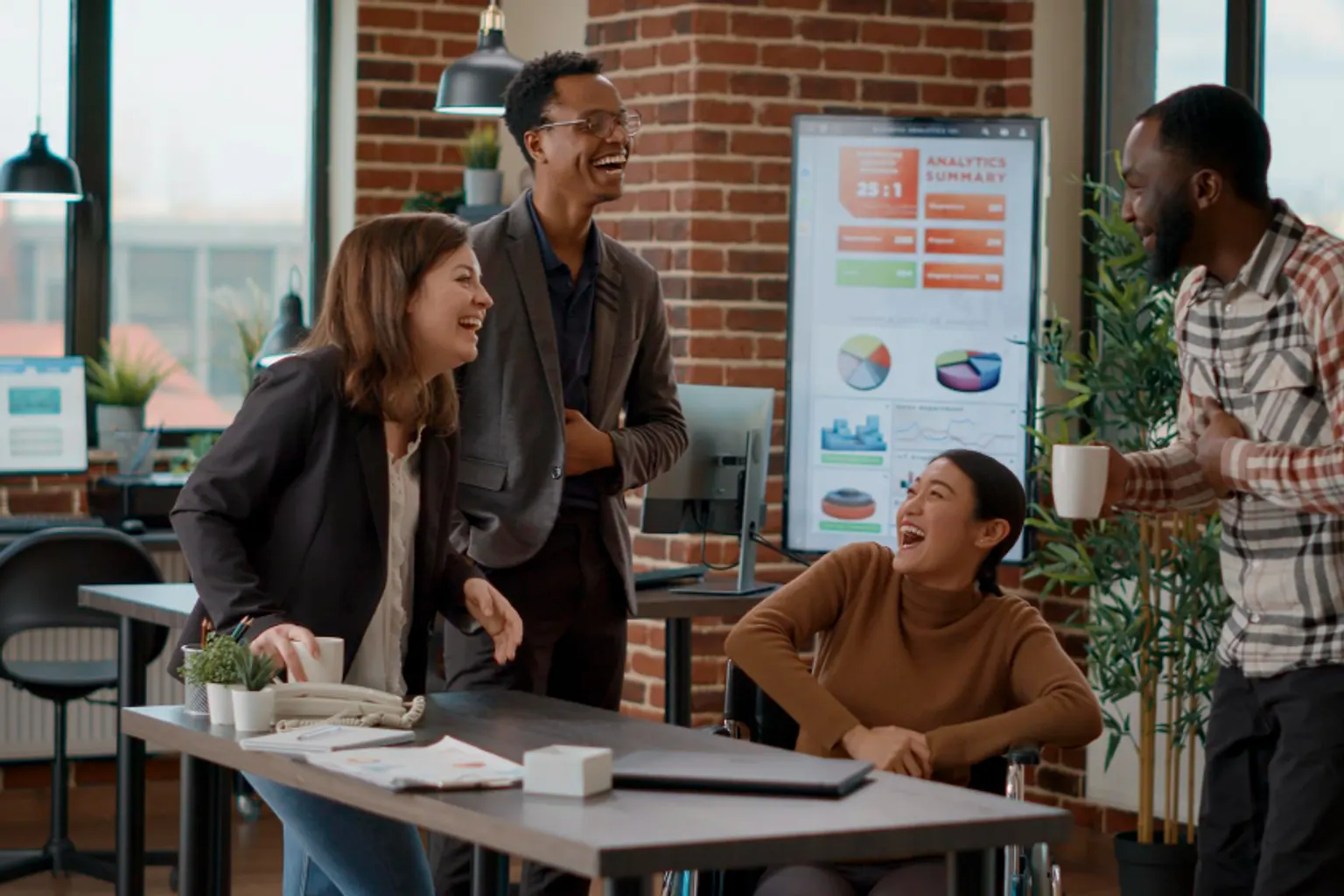 Des collègues échangent de manière informelle autour d’une table dans un espace de travail convivial.