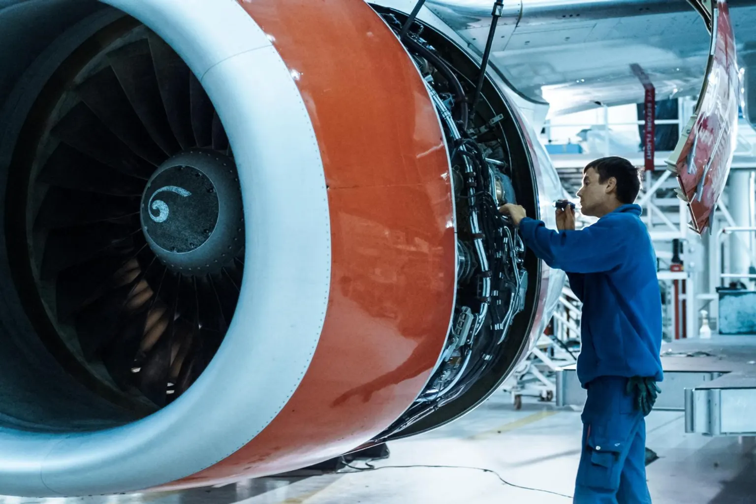Technicien de maintenance aéronautique contrôlant le moteur d’un avion dans un hangar de maintenance.