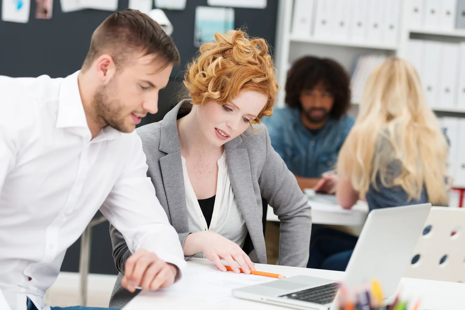 Une équipe d'entreprise échange autour d'un plan de communication affiché sur un écran.