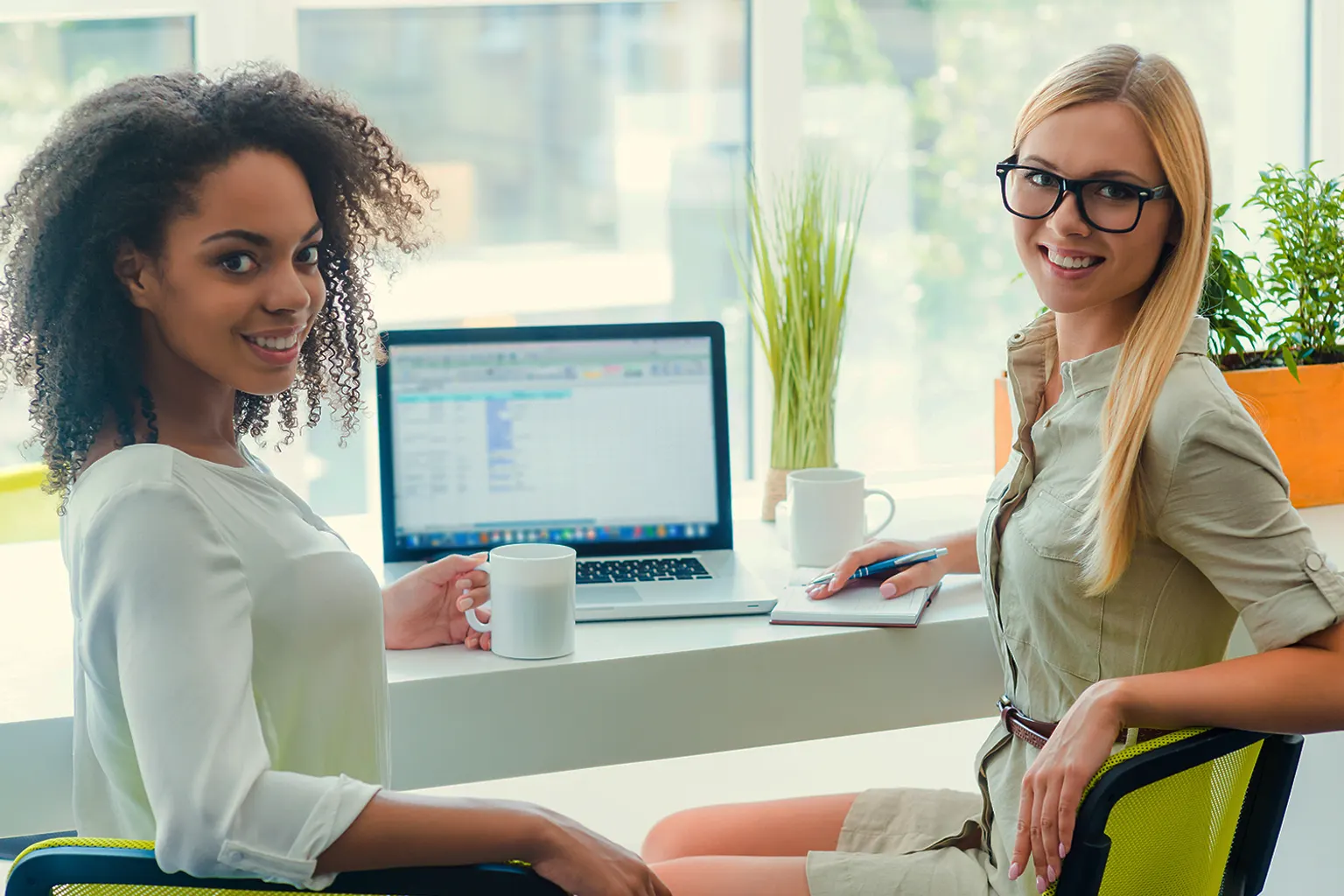 Entrepreneure analysant les résultats d'une campagne publicitaire sur son ordinateur, avec des supports imprimés sur un bureau.