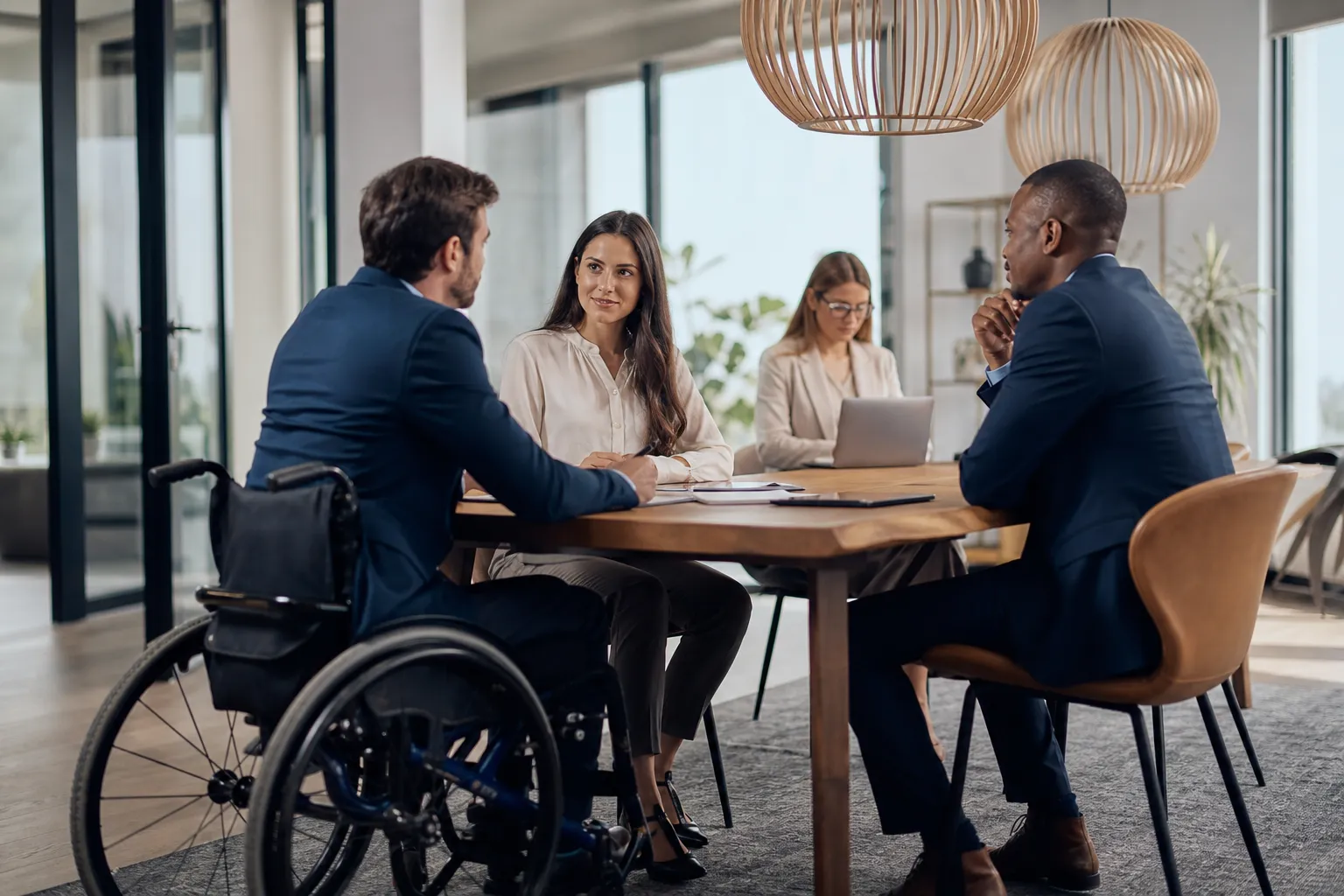 Une responsable des ressources humaines échange avec un collaborateur en situation de handicap dans un bureau lumineux et accessible.