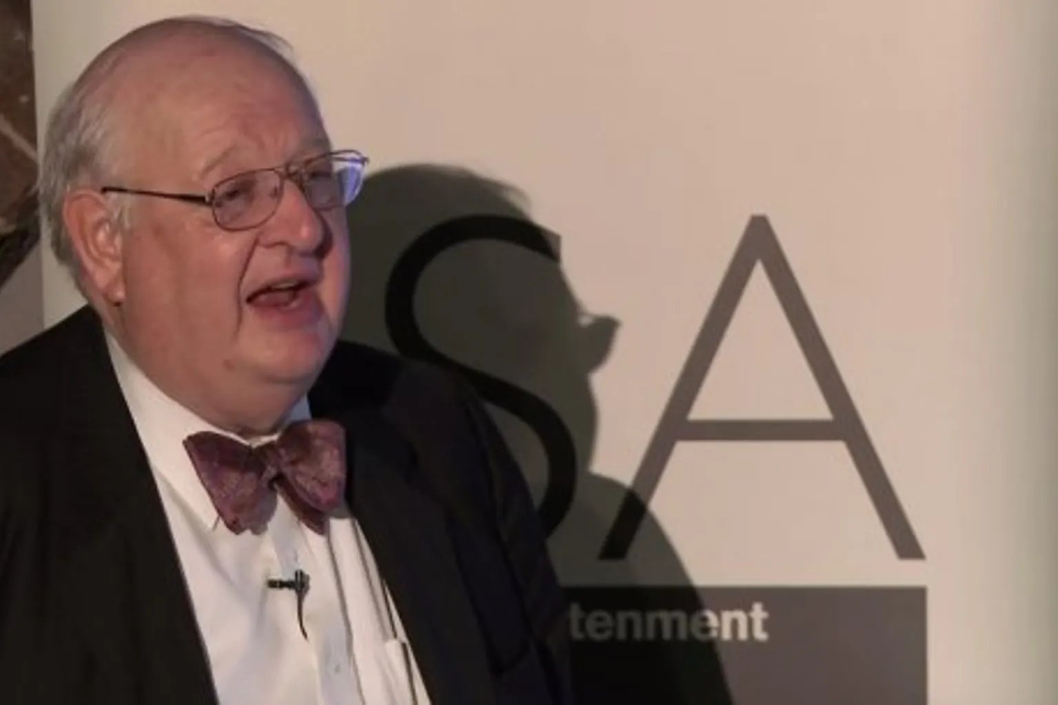 Portrait symbolique d’Angus Deaton devant des données sur la consommation et la pauvreté des ménages.