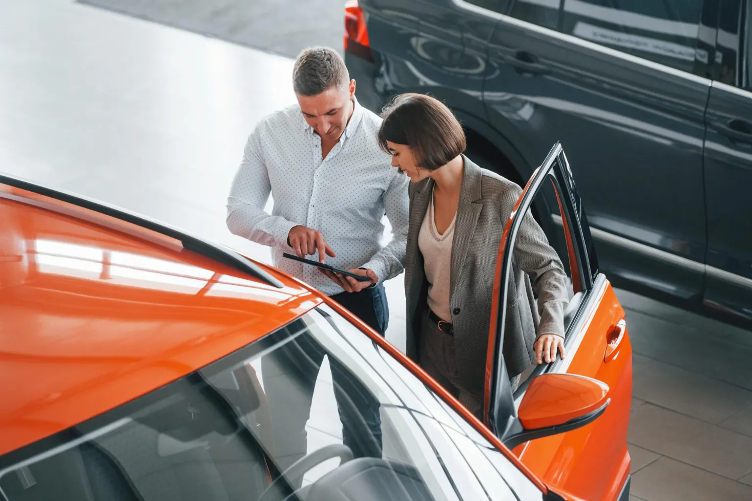 Un professionnel de la vente automobile examine des véhicules exposés dans le parc sécurisé de sa concession.