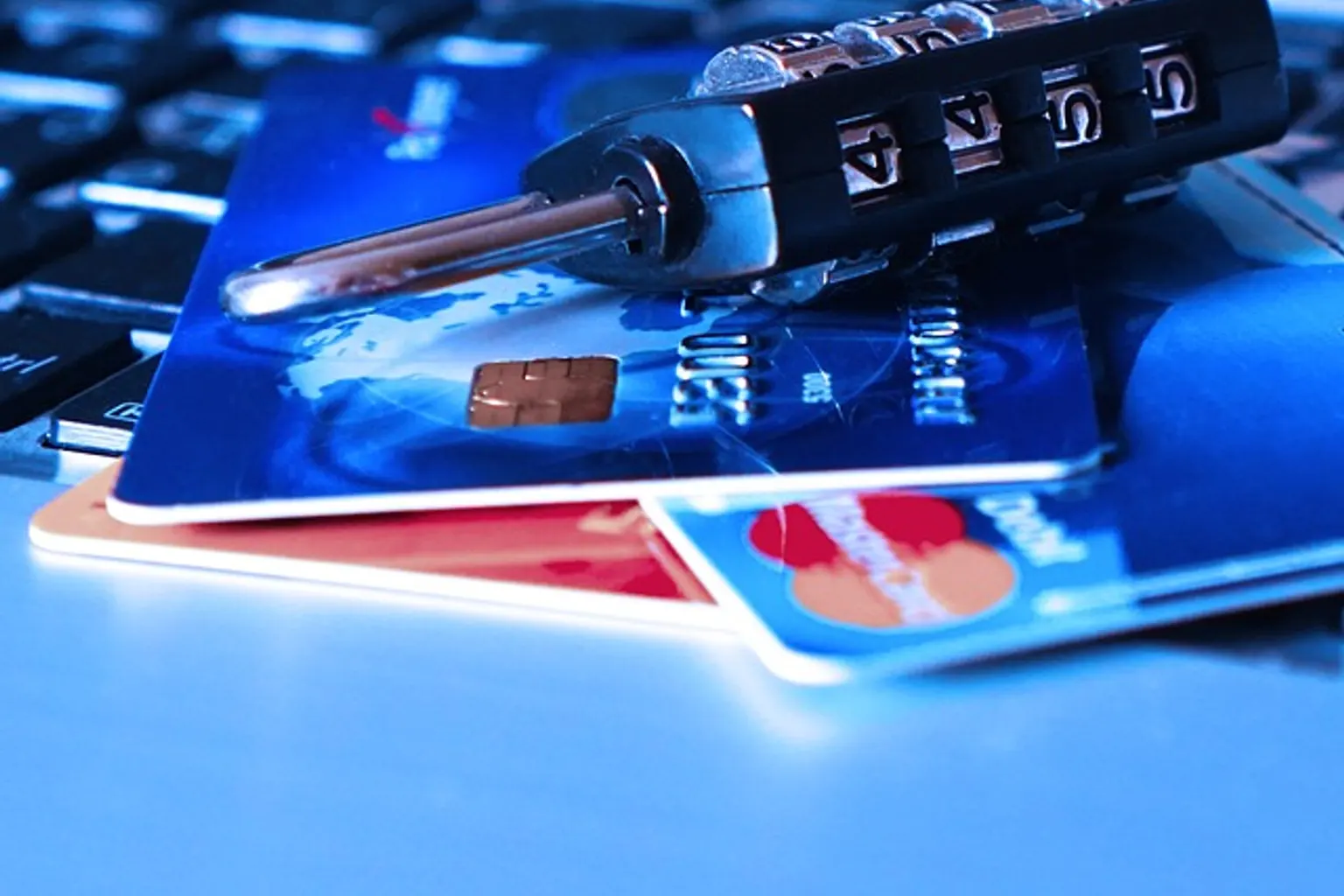 Une personne protège sa carte bancaire et son téléphone devant un ordinateur affichant une alerte de sécurité.