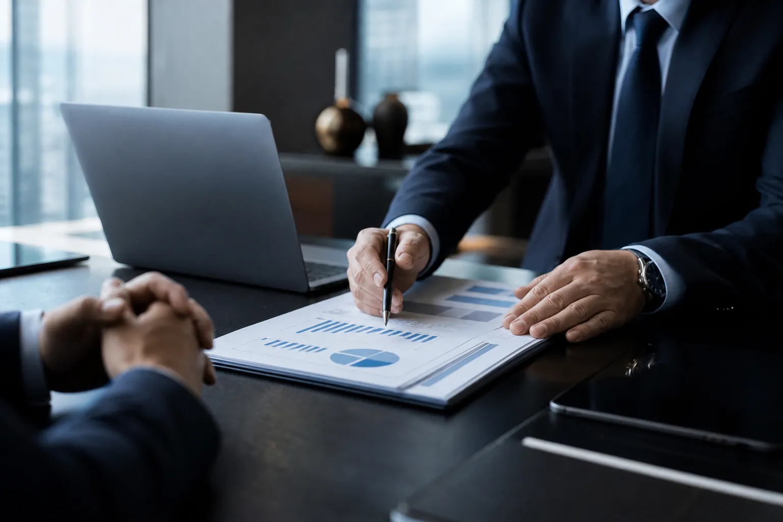 Deux personnes en réunion examinant des graphiques financiers et un tableau de chiffres sur une tablette, dans un bureau moderne.
